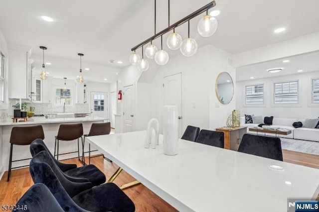 kitchen with a breakfast bar area, light countertops, glass insert cabinets, white cabinetry, and open floor plan