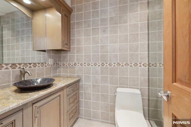 bathroom featuring vanity, tile walls, and toilet