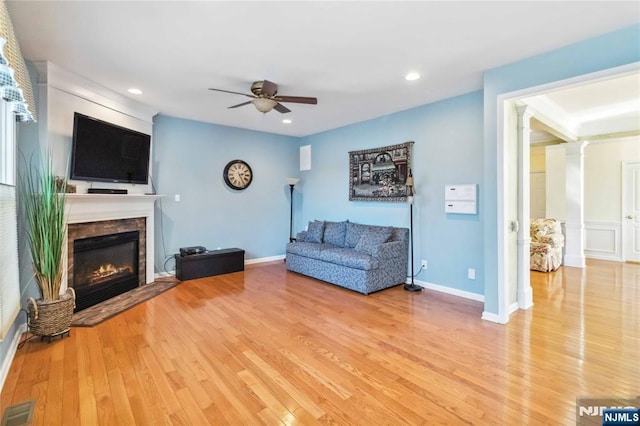 unfurnished living room with a glass covered fireplace, visible vents, light wood finished floors, and ceiling fan