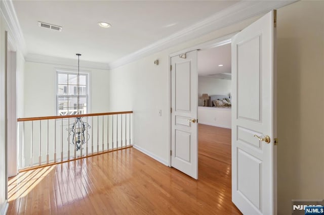 unfurnished room featuring visible vents, crown molding, light wood finished floors, baseboards, and a chandelier