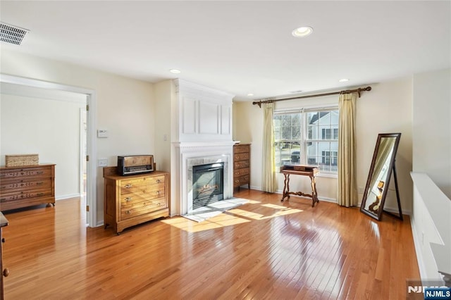 living room with visible vents, a fireplace with flush hearth, recessed lighting, light wood finished floors, and baseboards