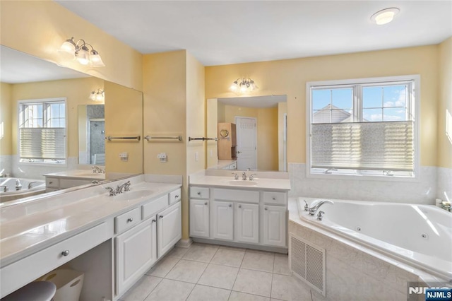 full bathroom featuring tile patterned flooring, a tub with jets, two vanities, and a sink