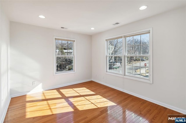 unfurnished room featuring visible vents, baseboards, and wood-type flooring