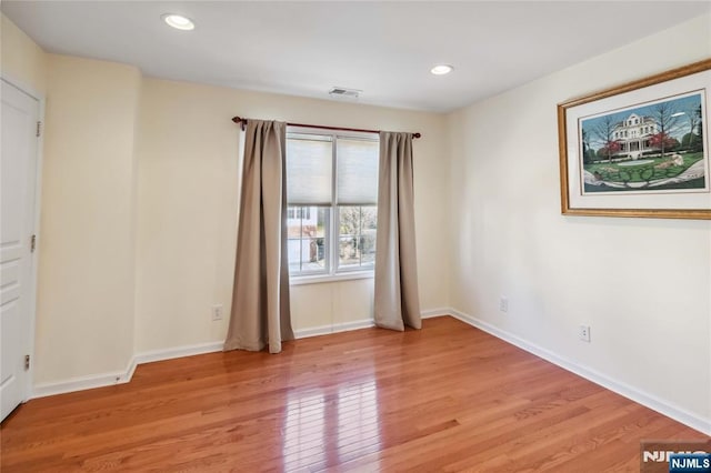 spare room featuring light wood-type flooring, visible vents, baseboards, and recessed lighting