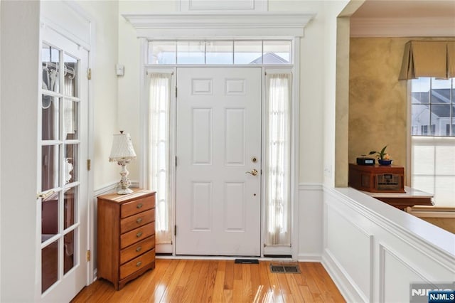 foyer featuring crown molding, light wood-style floors, and visible vents