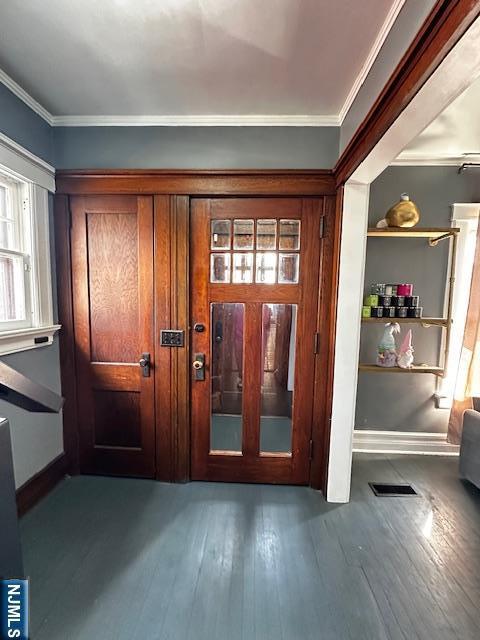 entryway featuring visible vents, wood finished floors, baseboards, and ornamental molding