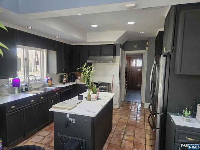 kitchen with a sink, a center island, under cabinet range hood, decorative backsplash, and dark cabinets