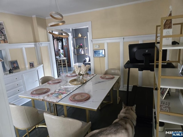 dining area featuring crown molding, a decorative wall, and wainscoting