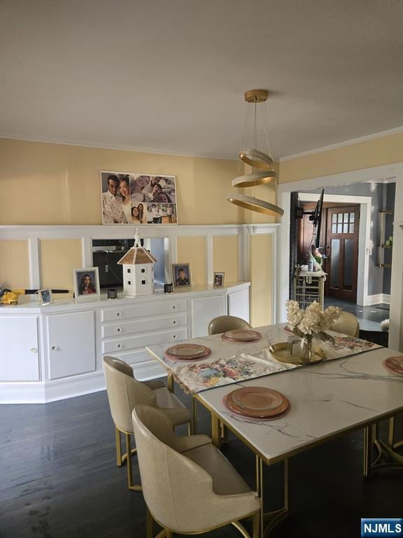 dining area with dark wood-type flooring and ornamental molding