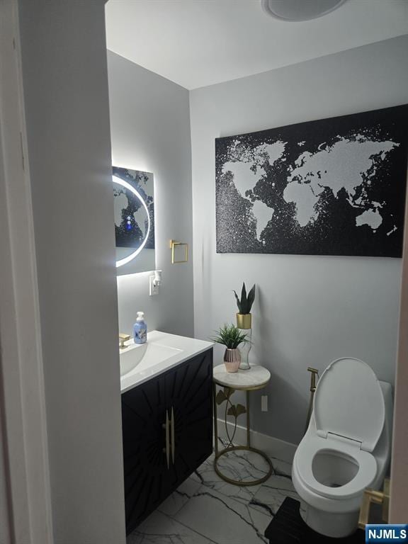 half bath featuring marble finish floor, toilet, vanity, and baseboards