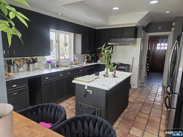 kitchen with gas stove, a kitchen island, a sink, under cabinet range hood, and dark cabinets