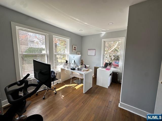 office featuring dark wood finished floors, radiator heating unit, and baseboards