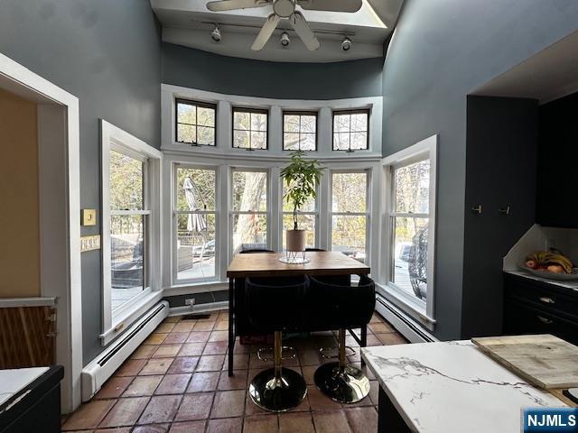 sunroom with a baseboard radiator and ceiling fan