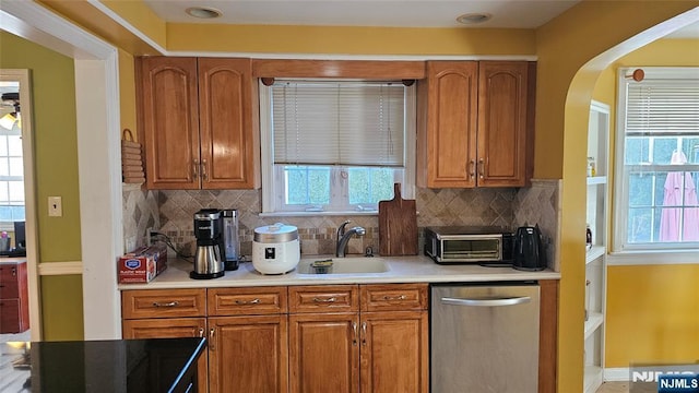 kitchen featuring a toaster, dishwasher, light countertops, brown cabinets, and a sink