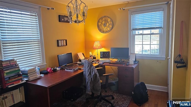 office space featuring baseboards, a notable chandelier, and wood finished floors