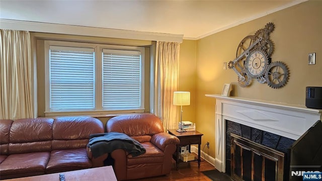 living area featuring a glass covered fireplace, baseboards, and ornamental molding