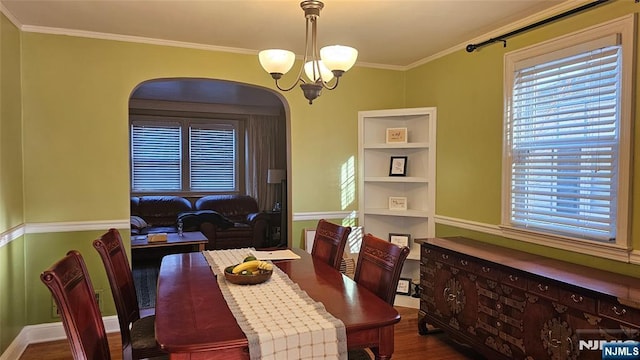 dining space featuring crown molding, wood finished floors, arched walkways, and a chandelier