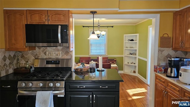 kitchen featuring light wood-type flooring, brown cabinets, appliances with stainless steel finishes, and ornamental molding