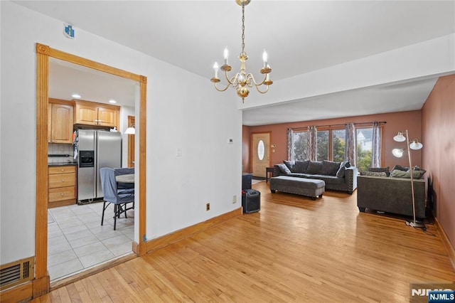 living area featuring an inviting chandelier, light wood-style flooring, baseboards, and visible vents