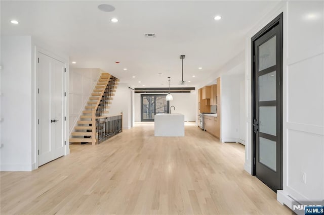 unfurnished living room featuring recessed lighting, visible vents, light wood-style flooring, and stairs