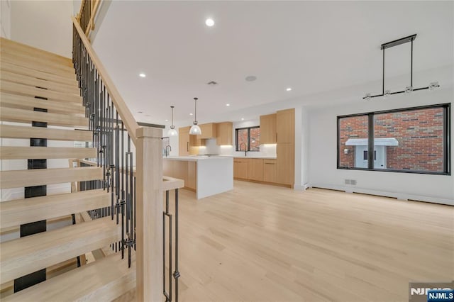 interior space featuring light brown cabinets, a kitchen island, light wood-type flooring, light countertops, and recessed lighting