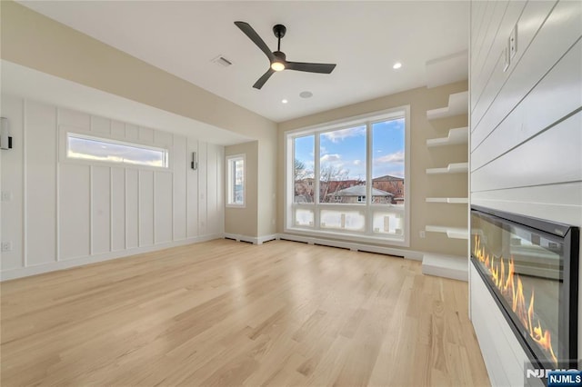 unfurnished living room featuring baseboards, recessed lighting, ceiling fan, light wood-style floors, and a glass covered fireplace