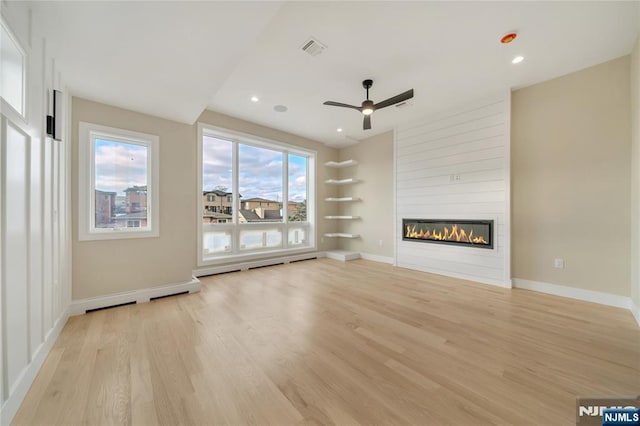 unfurnished living room featuring visible vents, baseboards, a large fireplace, and light wood-style floors