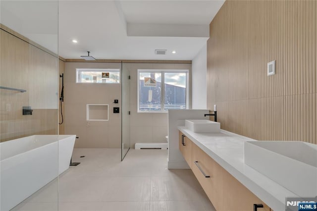 bathroom with a sink, visible vents, tile walls, and a walk in shower