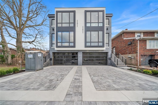 view of front of property featuring stairway, decorative driveway, a garage, and stucco siding