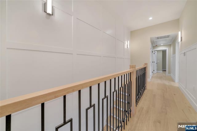 corridor featuring visible vents, attic access, recessed lighting, light wood-style floors, and a decorative wall