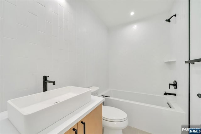 bathroom featuring tile walls, tub / shower combination, toilet, and vanity