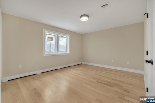 spare room featuring light wood finished floors, visible vents, baseboards, and a baseboard radiator