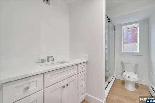 full bath featuring vanity, wood finished floors, baseboards, a stall shower, and toilet