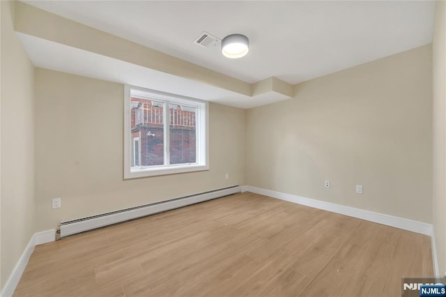 empty room featuring visible vents, baseboards, light wood-style floors, and a baseboard radiator