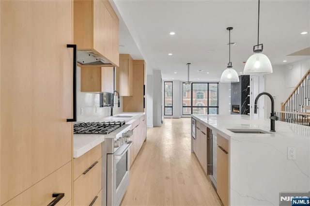 kitchen featuring light brown cabinets, modern cabinets, range with gas cooktop, and a sink