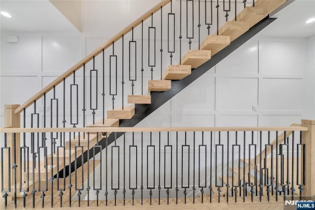 stairway with a decorative wall and recessed lighting