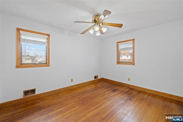 empty room featuring visible vents, baseboards, ceiling fan, and hardwood / wood-style flooring