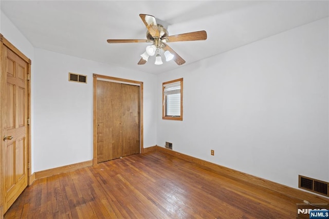 unfurnished bedroom with a closet, visible vents, and hardwood / wood-style flooring