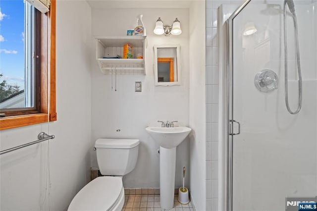 bathroom featuring tile patterned floors, toilet, a shower stall, and a sink