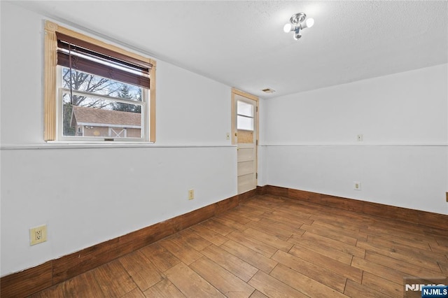 unfurnished room featuring visible vents, wood finished floors, and baseboards