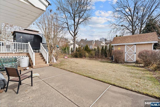 view of patio with a storage unit, an outbuilding, a wooden deck, and stairway