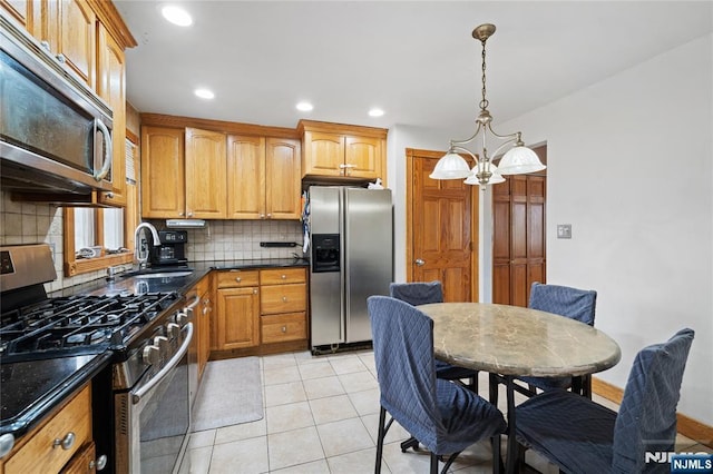 kitchen featuring light tile patterned floors, decorative backsplash, appliances with stainless steel finishes, a notable chandelier, and a sink