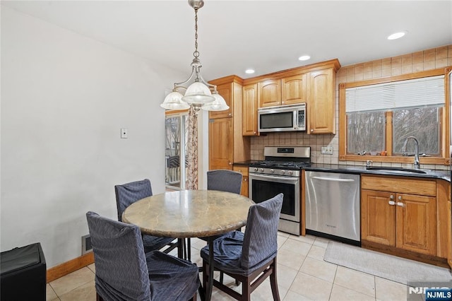 kitchen with dark countertops, light tile patterned floors, decorative backsplash, appliances with stainless steel finishes, and a sink