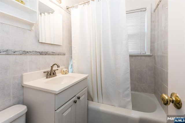 bathroom featuring tile walls, vanity, toilet, and shower / tub combo