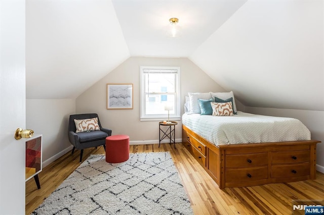 bedroom featuring baseboards, vaulted ceiling, and light wood finished floors