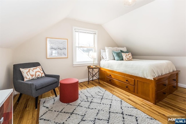 bedroom with light wood-type flooring, lofted ceiling, and baseboards