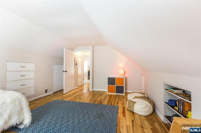 bedroom with vaulted ceiling, baseboards, visible vents, and wood finished floors