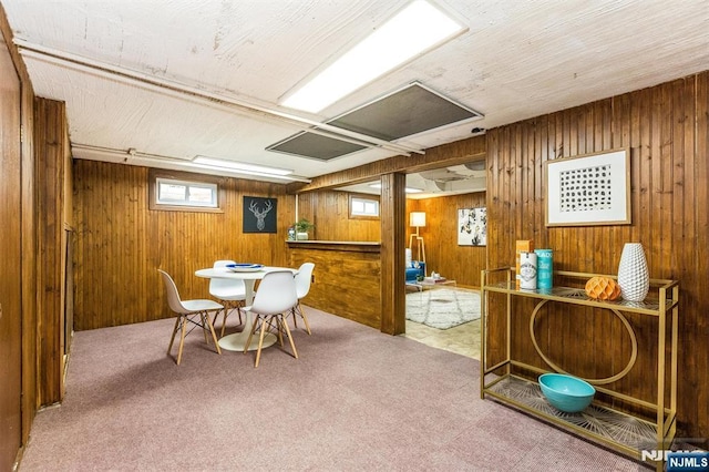 carpeted dining room with wood walls