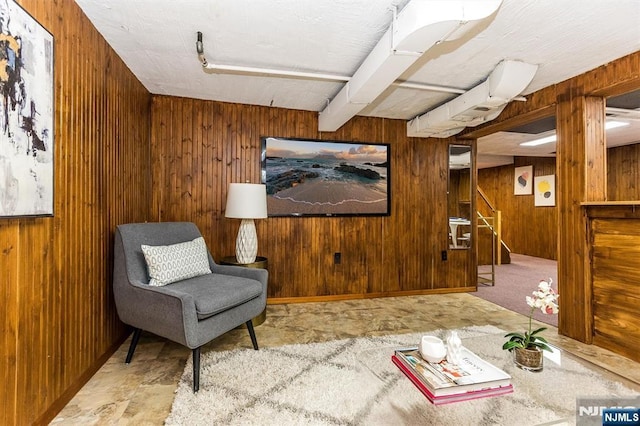 living area featuring stairway, beamed ceiling, and wood walls