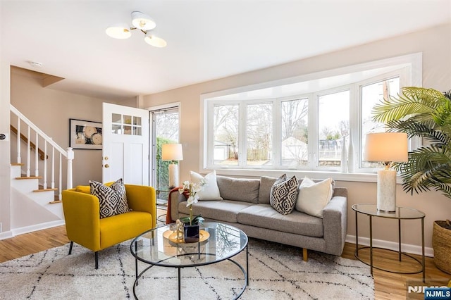 living area with baseboards, wood finished floors, and stairs